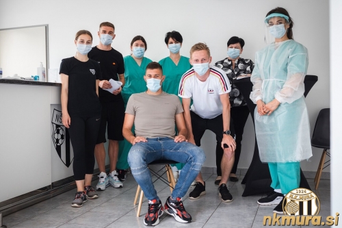 Skupinska fotografija zdravstvenih delavcev in Murašev v prostorih kluba.